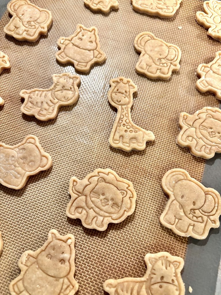 variety of various animal shaped sourdough discard animal crackers on a brown baking sheet