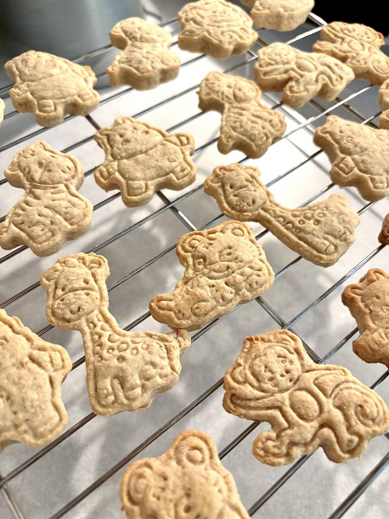 Many different animal shaped animal crackers on a metal cooling rack